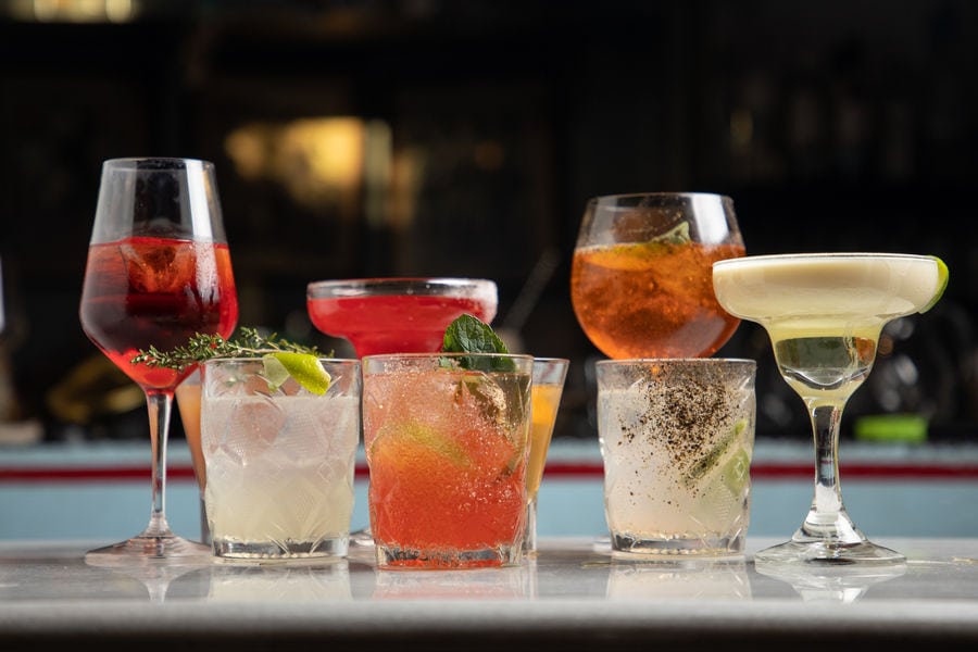 A captivating display unfolds, showcasing the artistry of mixology at Ramon Bar. Seven vibrant cocktails stand tall, each a masterpiece of flavors and colors.